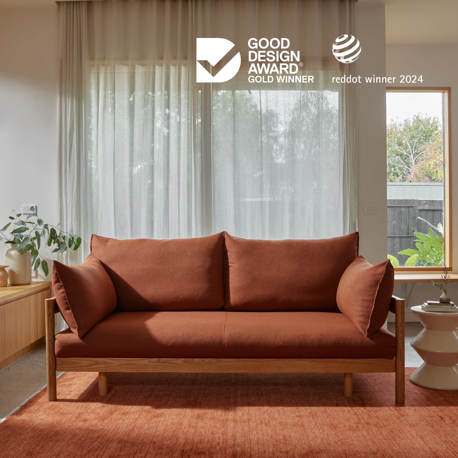 sofa bed in the terracotta colour with the Good Design Award Gold Winner and Red Dot Winner badges at the top